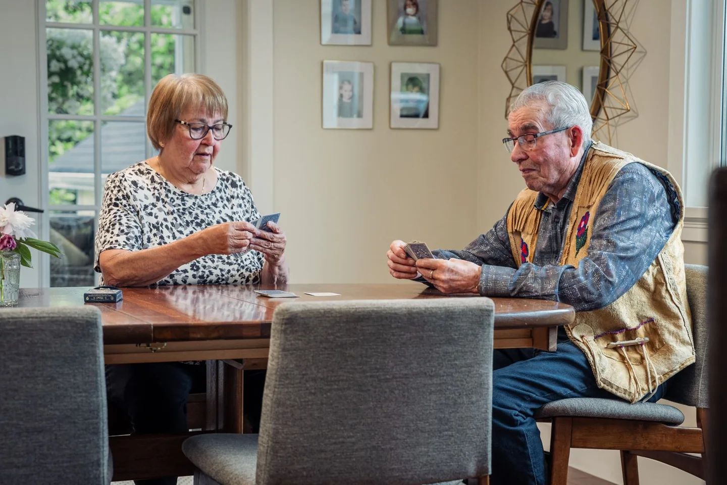 Two older adults enjoying a card game at a table indoors