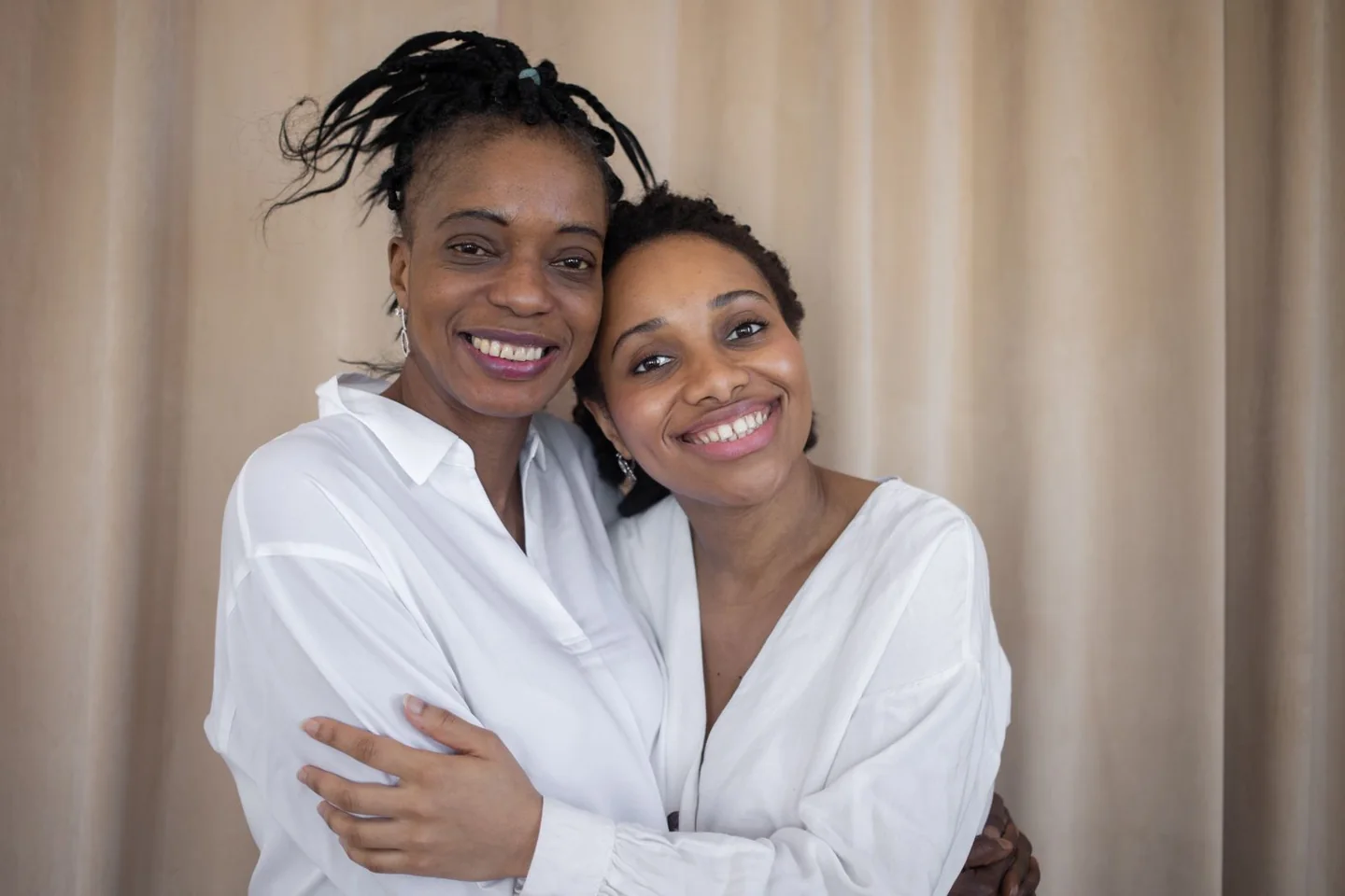 A mother and adult daughter sharing an embrace indoors